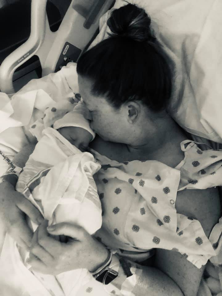 Hypno mom Abbey in bed holding and kissing her newborn baby.