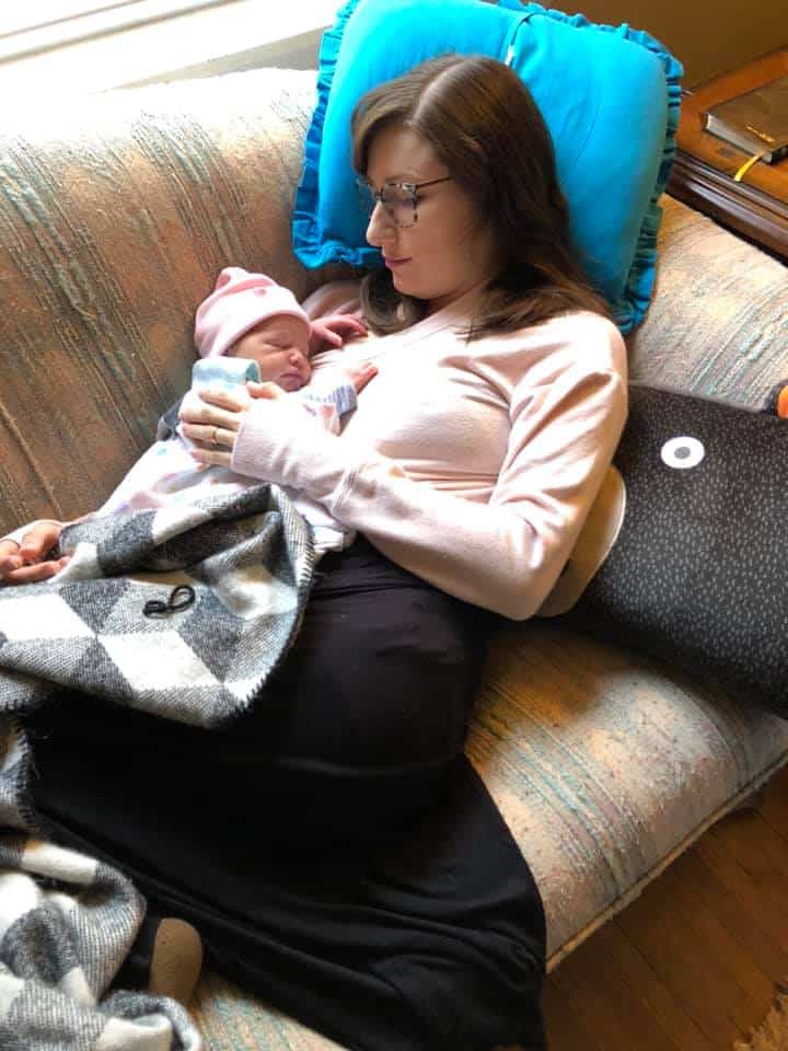 Hypno-mom Ainsley laying on couch holding newborn baby.