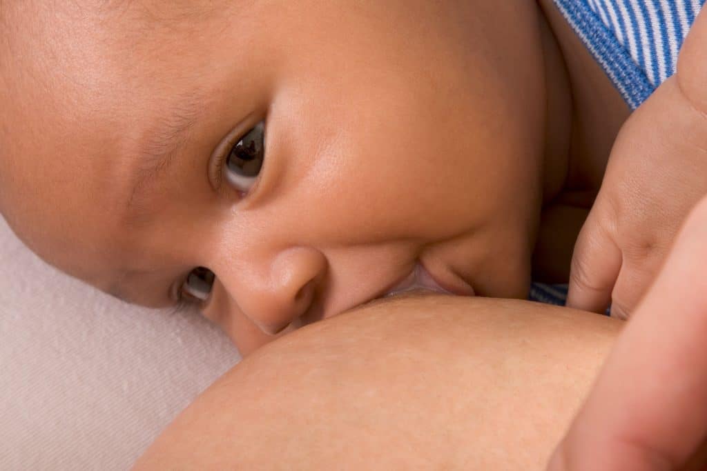 A close-up of a baby breastfeeding, peacefully latched at the breast.