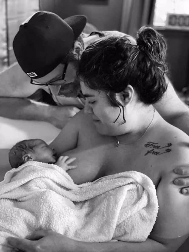black and white photo of couple admiring their newborn baby and smiling