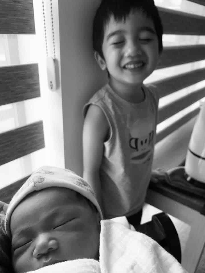 Newborn baby and big brother smiling in black and white