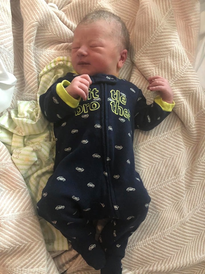 Danielle's baby boy in black zip up pajamas with cars on them