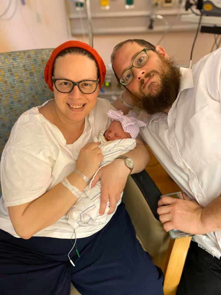 Hypno-mom Duby and partner sitting in chair in hospital holding newborn baby