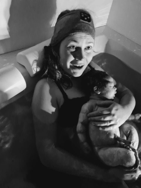 New parent holding baby in tub after birth center waterbirth