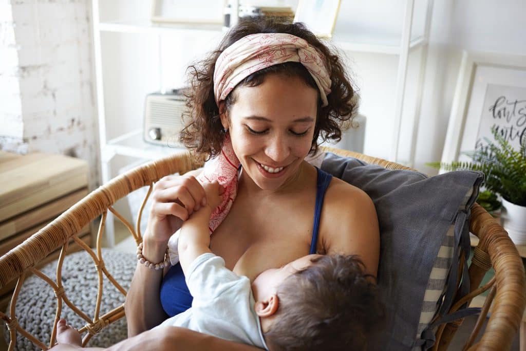 Mother breastfeeding her baby while smiling.