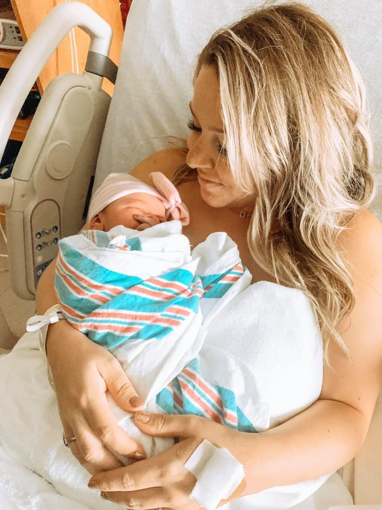 Hypno-mom sitting up in hospital bed holding her swaddled newborn