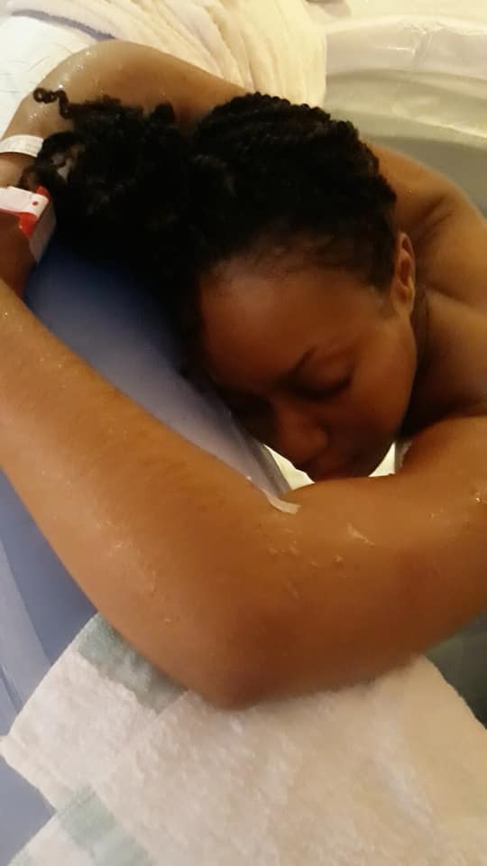 Hypno-mom Candace in birth tub leaning over the edge resting her head.