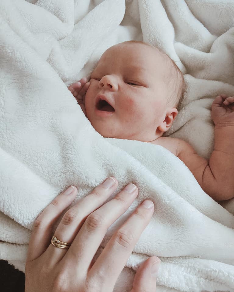 Newborn baby laying on a fuzzy white blanket