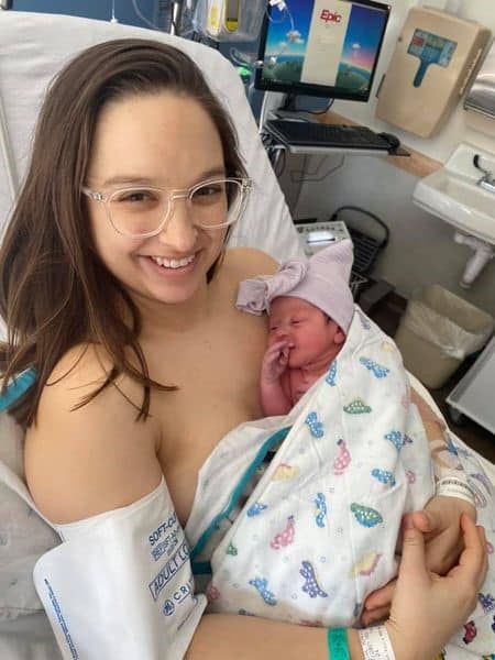 Hypnobabies Student Skin to Skin with newborn baby smiling and wearing glasses with a blood pressure cuff around arm.