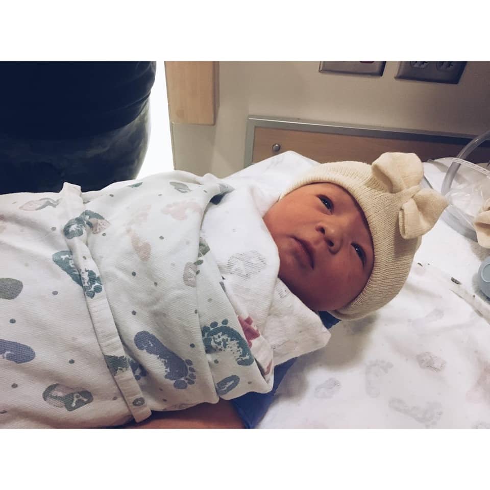 Hypno-mom Kaylee's newborn baby wearing hat and wrapped in blanket covered in little footprints.