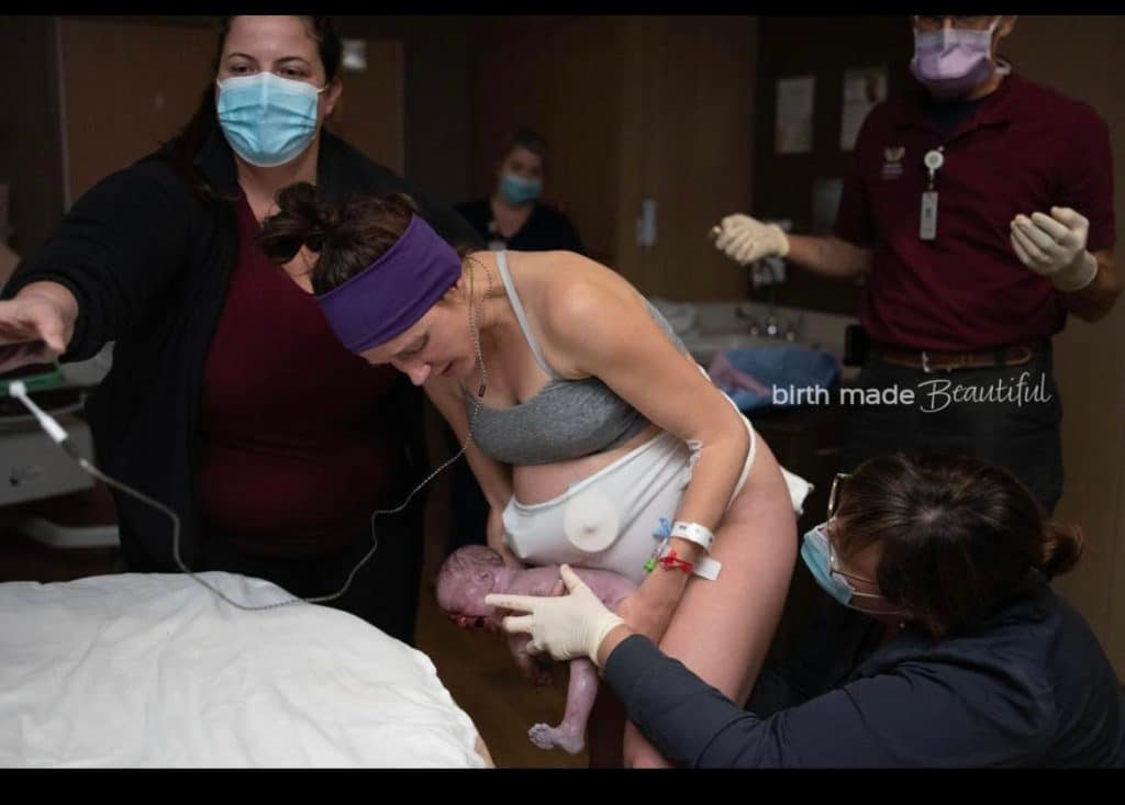 Hypnobabies parent standing and after just catching her first twin right after breech birth