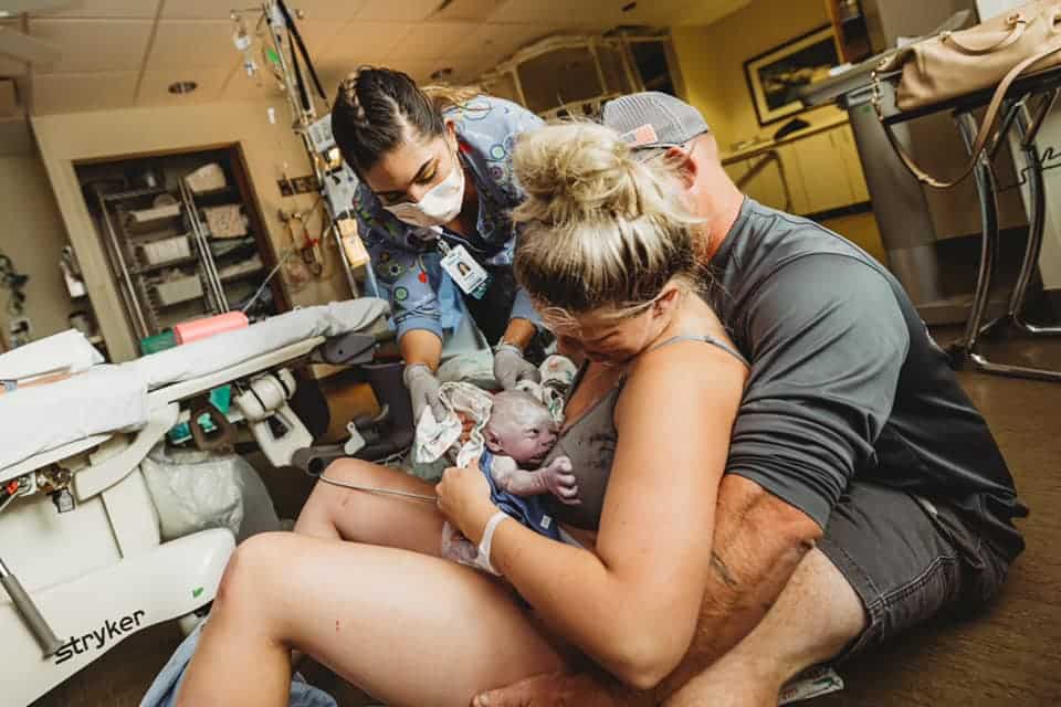 new parents with newborn right after birth with nurse supporting