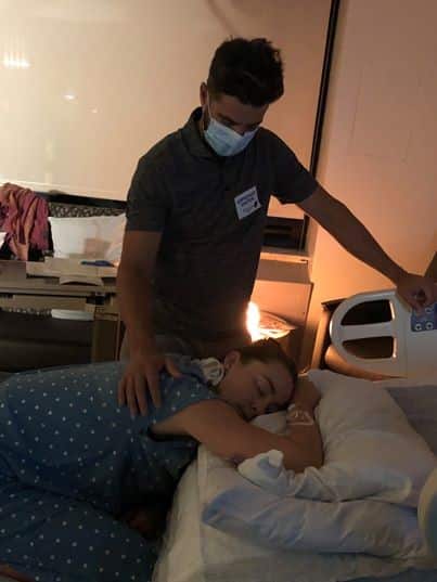 Hypno-mom on hands and knees in bed with partner doing relax cue on her shoulder