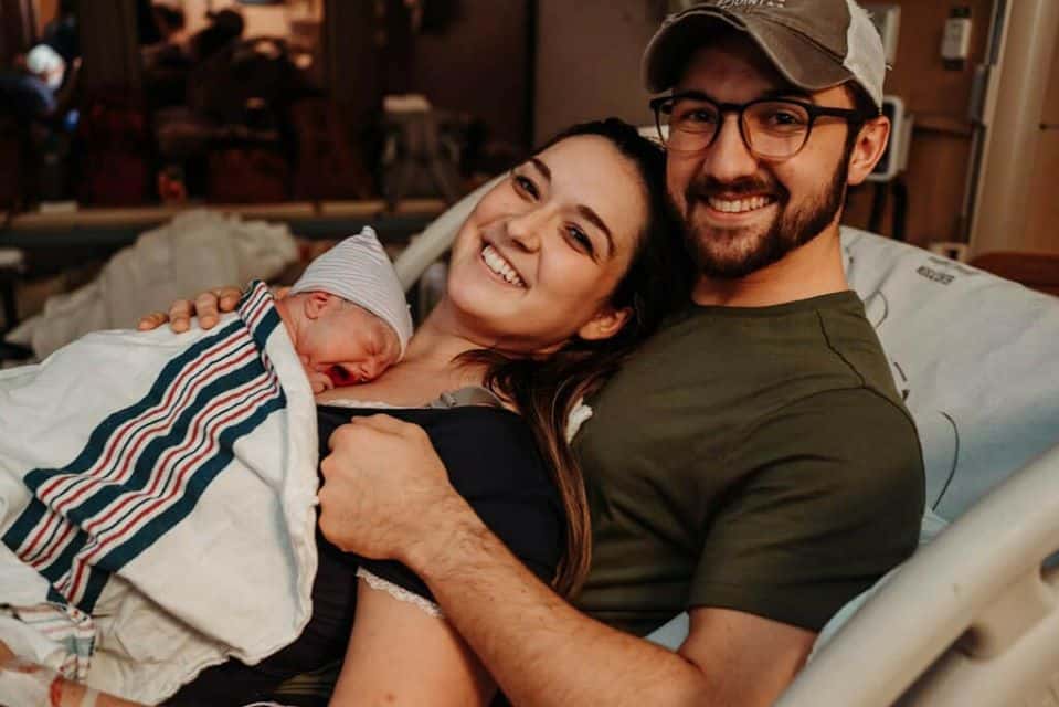 Hypno-family laying in hospital bed smiling