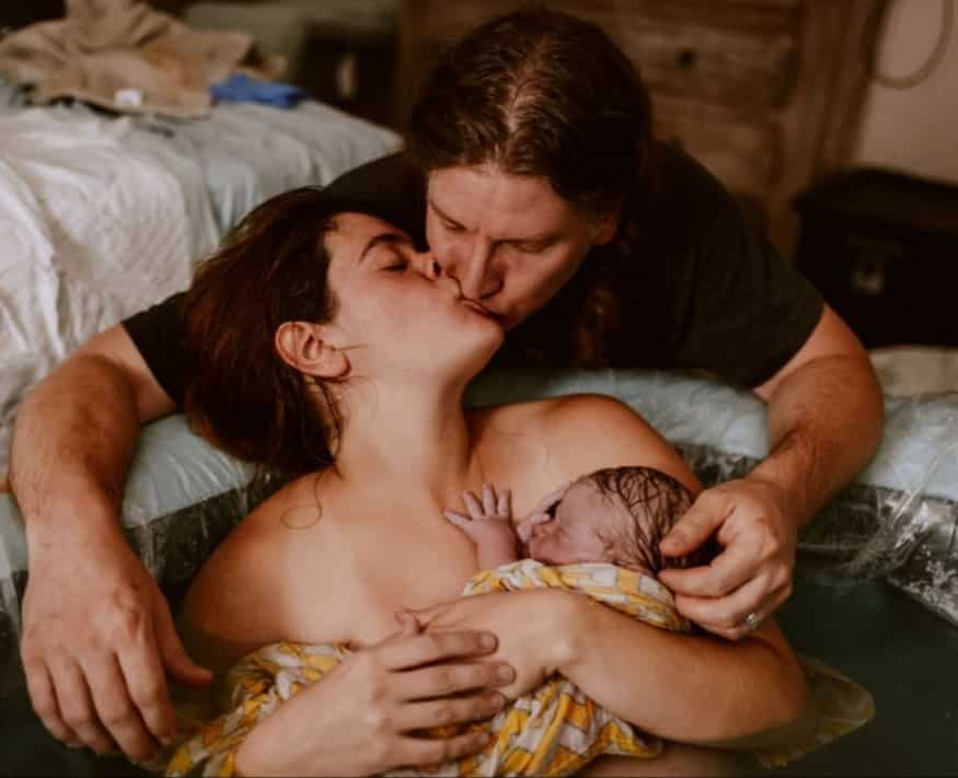Hypno mom in birth tub with newborn kissing birth partner