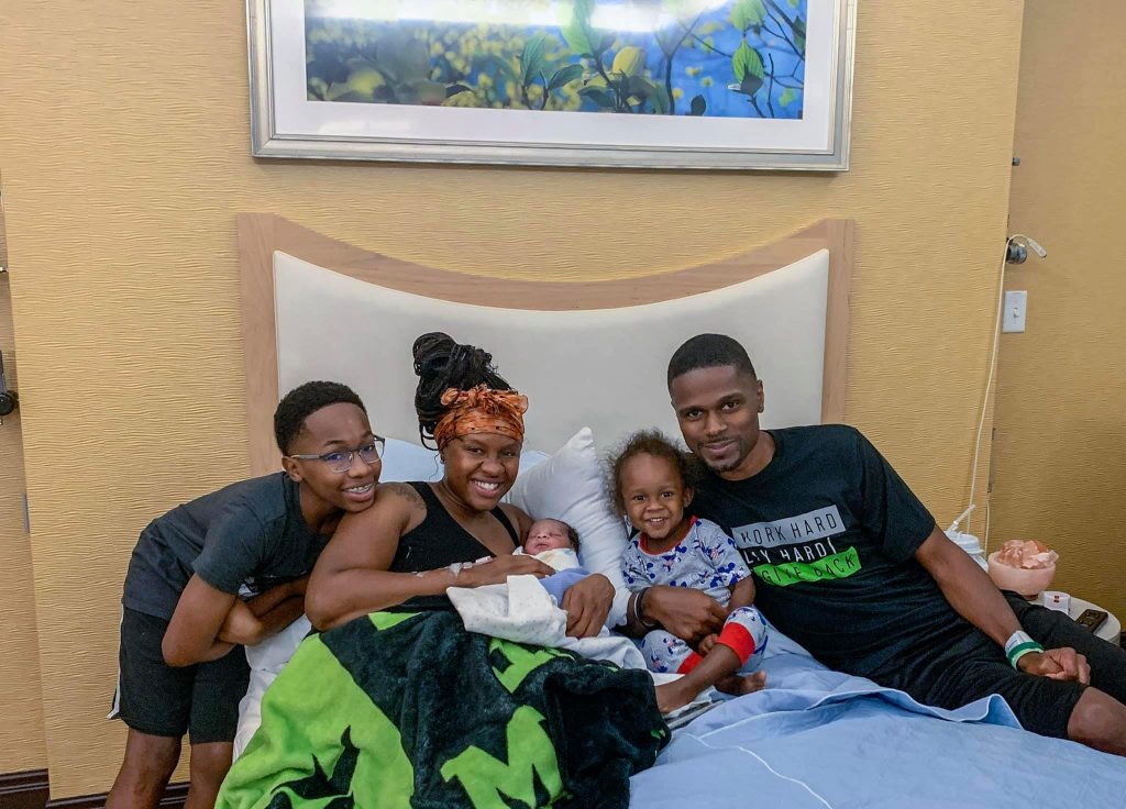 Hypno-mom Rachel in bed with newborn baby and rest of her family.