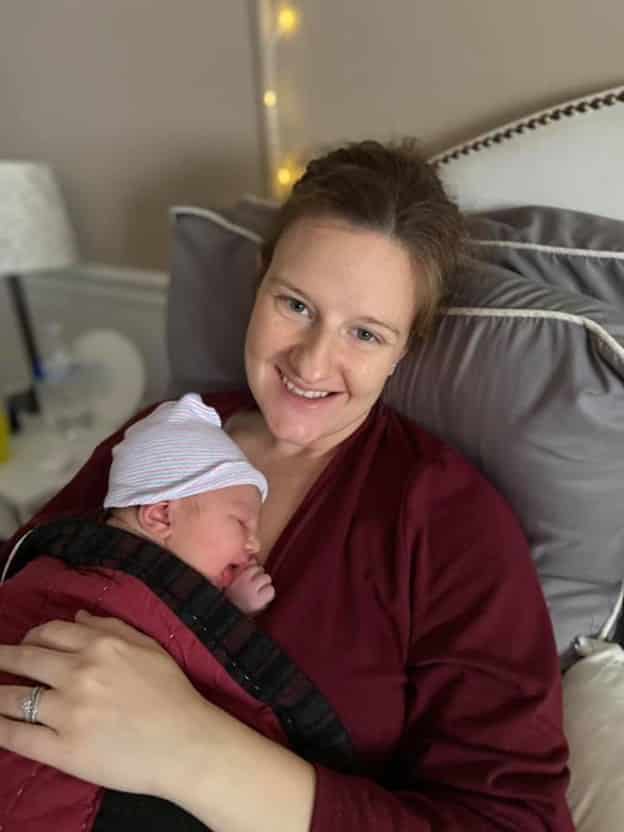 new parent with baby on chest and smiling