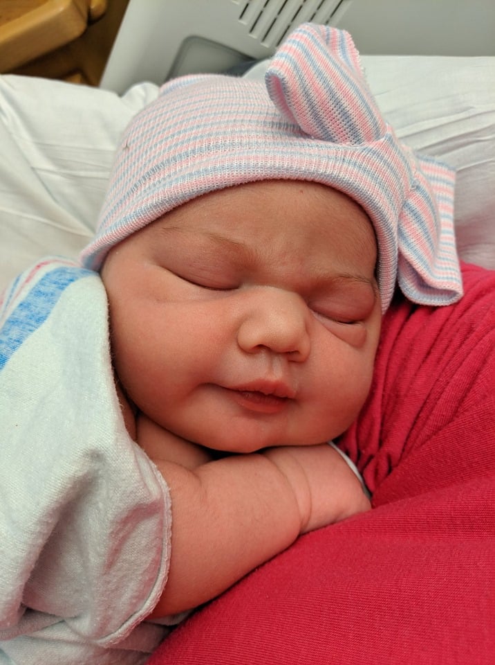 Hypno-mom Sarah's newborn with a hospital hat on her head.