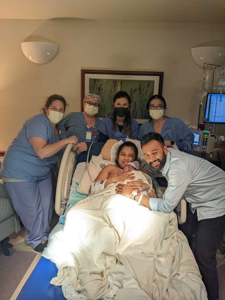 New Hypnobabies parents with newborn baby surrounding by hospital birth team wearing masks